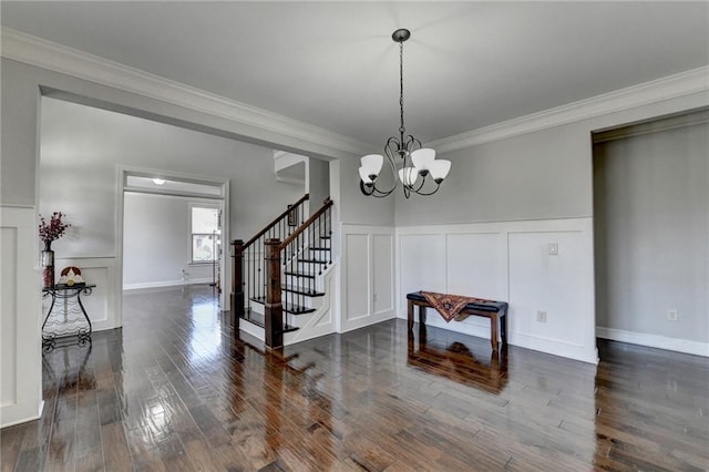 dining area with a decorative wall, an inviting chandelier, ornamental molding, stairway, and dark wood-style flooring