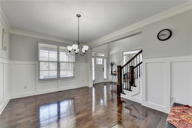 entrance foyer featuring a decorative wall, wainscoting, an inviting chandelier, and ornamental molding