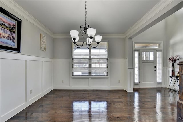 entryway with a decorative wall, a notable chandelier, and wainscoting