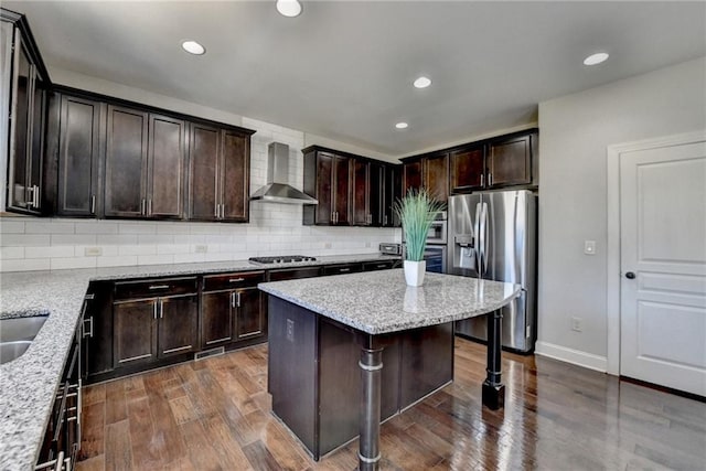 kitchen with tasteful backsplash, wall chimney range hood, a kitchen bar, and stainless steel appliances