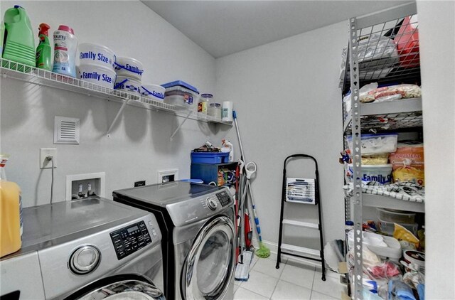 washroom with light tile patterned floors, separate washer and dryer, and laundry area