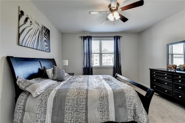 bedroom featuring ceiling fan, multiple windows, light colored carpet, and baseboards