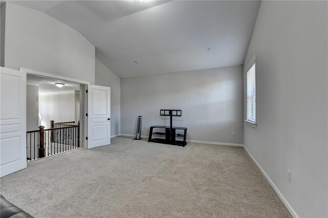 empty room with light carpet, baseboards, and lofted ceiling