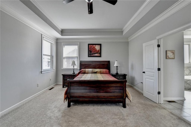 bedroom with visible vents, baseboards, light colored carpet, and a raised ceiling