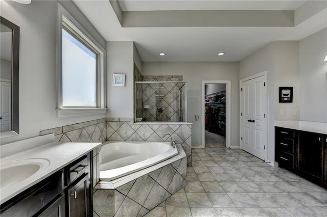 bathroom featuring a shower stall, a bath, two vanities, and a sink