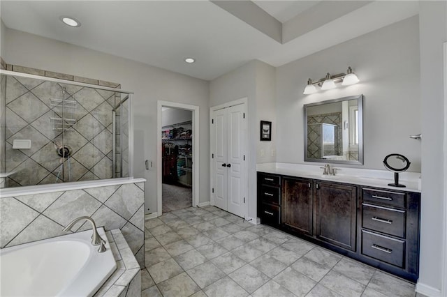 bathroom featuring vanity, recessed lighting, a shower stall, a walk in closet, and a bath