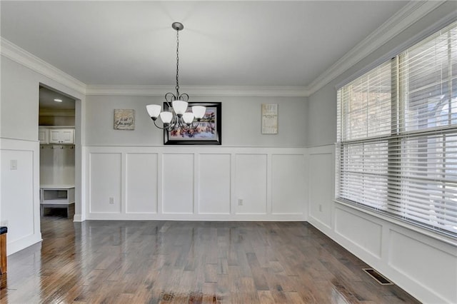 unfurnished dining area featuring a chandelier, crown molding, a decorative wall, and visible vents