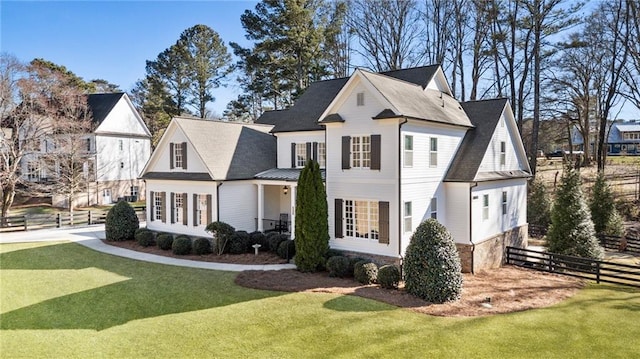 view of front facade featuring a front lawn, a standing seam roof, and fence