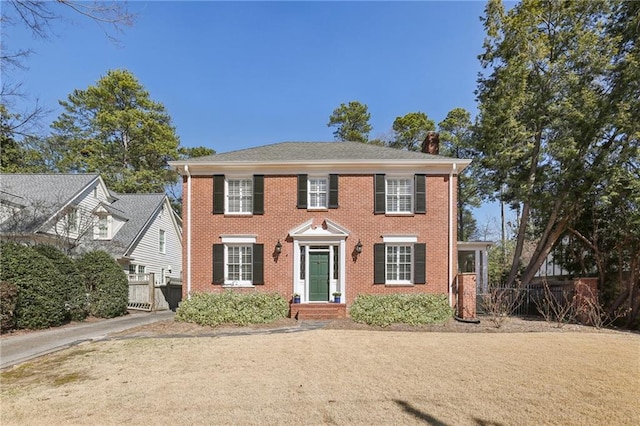 colonial inspired home featuring brick siding and fence