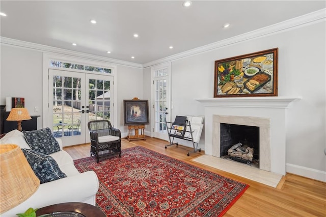 living area featuring a fireplace, ornamental molding, wood finished floors, and french doors