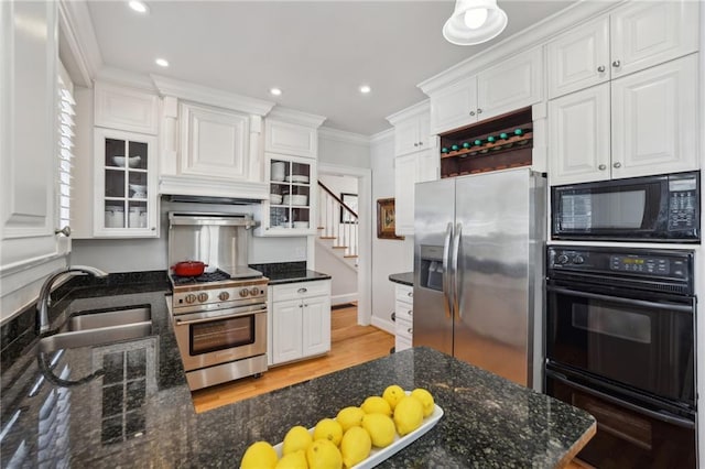 kitchen featuring white cabinets, glass insert cabinets, ornamental molding, black appliances, and a sink