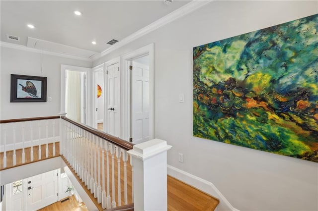 hallway with attic access, visible vents, ornamental molding, and an upstairs landing