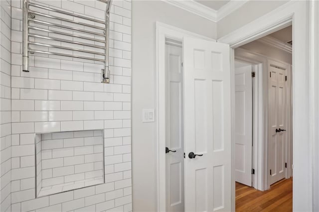 bathroom featuring crown molding, radiator heating unit, and wood finished floors