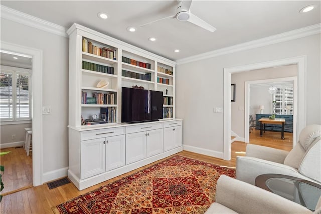 living area featuring recessed lighting, crown molding, light wood-style flooring, and ceiling fan with notable chandelier