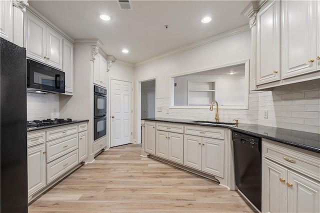 kitchen with black appliances, white cabinetry, and a sink