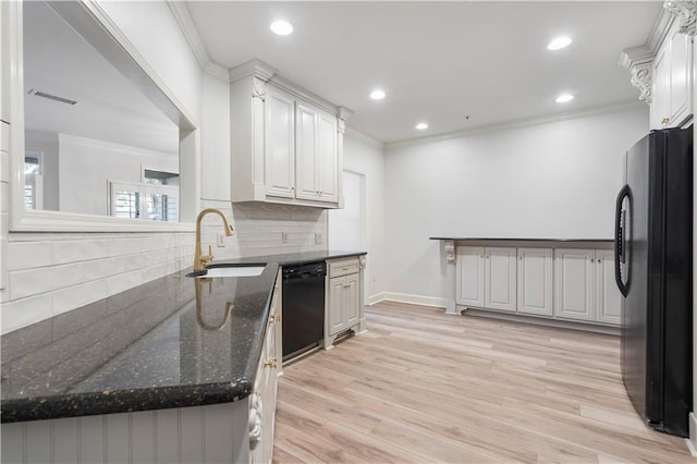 kitchen with light wood-style flooring, dark stone countertops, black appliances, white cabinetry, and a sink