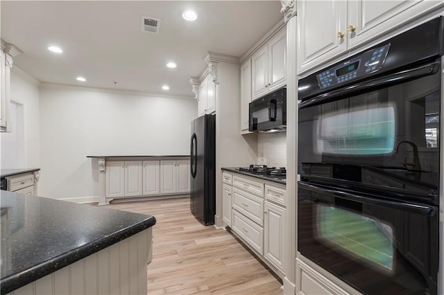 kitchen with light wood-style flooring, visible vents, white cabinets, ornamental molding, and black appliances