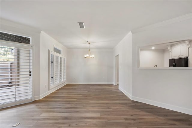 unfurnished dining area with a chandelier, ornamental molding, wood finished floors, and visible vents