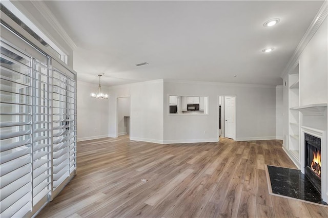 unfurnished living room featuring light wood-style flooring, a chandelier, crown molding, and a high end fireplace