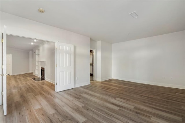 empty room featuring light wood-type flooring, a fireplace, and baseboards