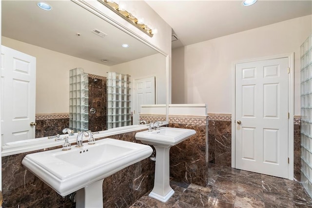 full bath with two sinks, recessed lighting, a wainscoted wall, tile walls, and marble finish floor