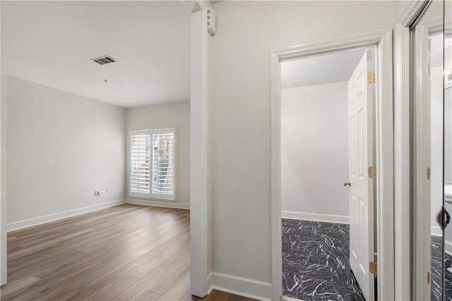 hall with baseboards, visible vents, and wood finished floors