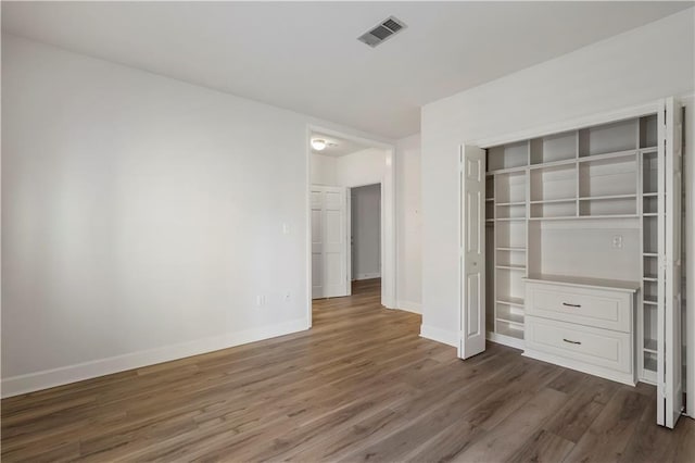 unfurnished bedroom with baseboards, a closet, visible vents, and dark wood-type flooring