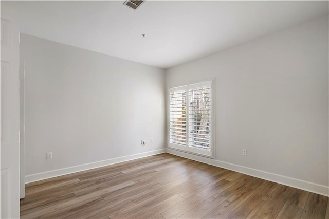 spare room with light wood-type flooring, baseboards, and visible vents