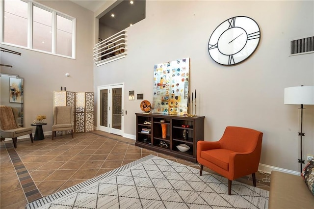 living area featuring tile patterned floors, visible vents, baseboards, and french doors