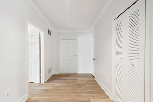 hallway with baseboards, light wood finished floors, visible vents, and crown molding