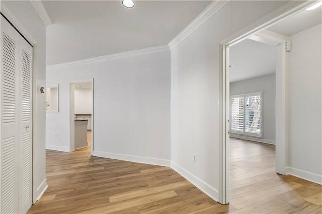 corridor with baseboards, light wood-style flooring, and crown molding