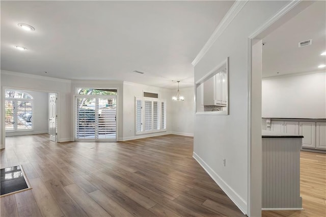 unfurnished living room featuring light wood-style flooring, plenty of natural light, visible vents, and crown molding