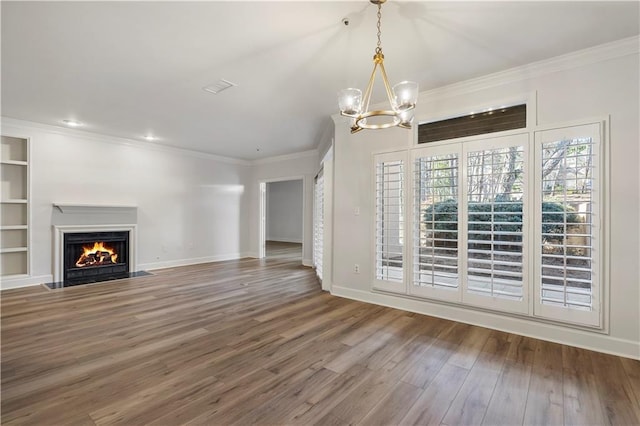 unfurnished living room with baseboards, a fireplace with flush hearth, ornamental molding, wood finished floors, and built in shelves