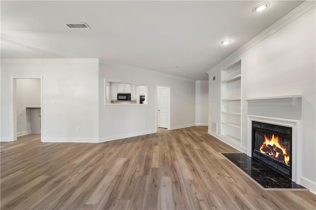 unfurnished living room with a fireplace, visible vents, built in features, baseboards, and light wood-type flooring