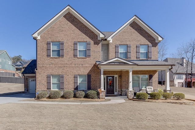 view of front of home with driveway, brick siding, and a porch