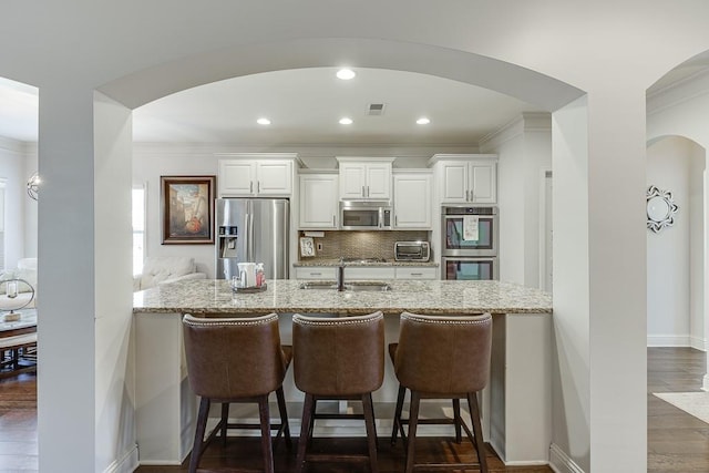 kitchen featuring light stone counters, appliances with stainless steel finishes, a sink, and white cabinetry