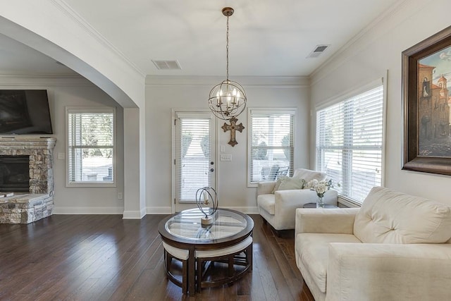 living area with visible vents, arched walkways, dark wood finished floors, crown molding, and a fireplace