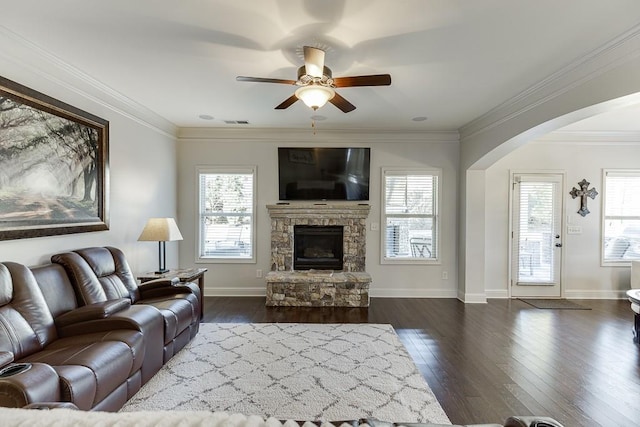 living room with arched walkways, ornamental molding, a fireplace, and a wealth of natural light