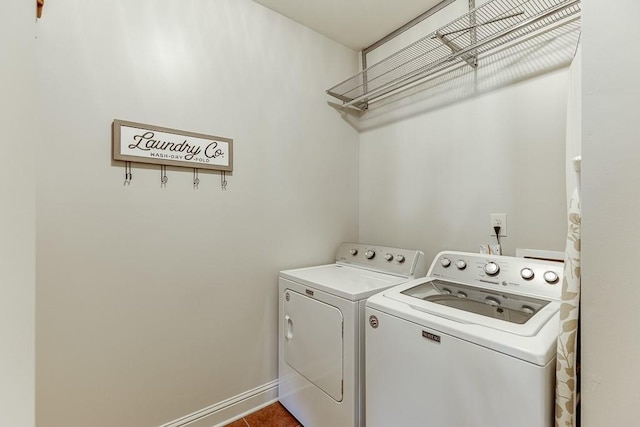 laundry room with laundry area, tile patterned flooring, washing machine and dryer, and baseboards