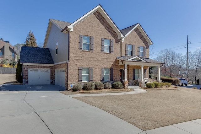 view of front of property featuring covered porch, driveway, brick siding, and an attached garage