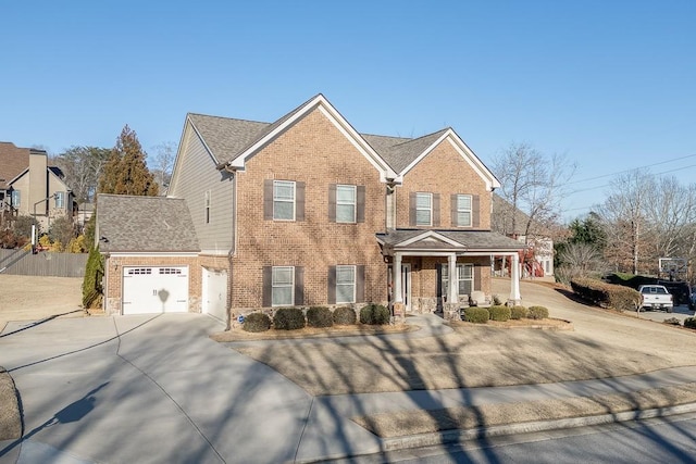 traditional-style home with an attached garage, covered porch, concrete driveway, and brick siding