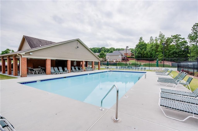 community pool with a patio area and fence