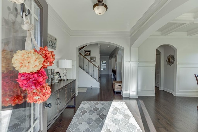 entrance foyer with ornamental molding, dark wood-type flooring, arched walkways, and stairs