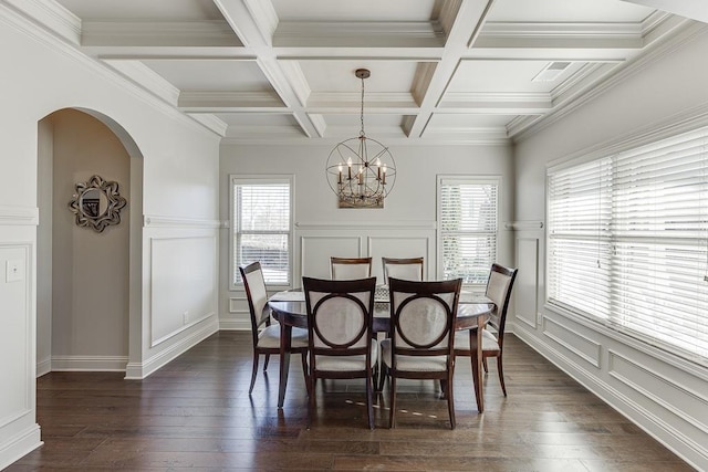 dining area featuring arched walkways, dark wood finished floors, a chandelier, a decorative wall, and beam ceiling