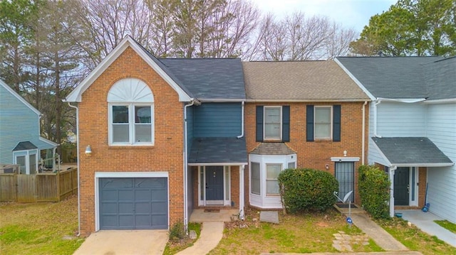 view of property with driveway, brick siding, an attached garage, and fence