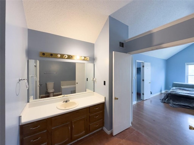 ensuite bathroom featuring visible vents, toilet, vaulted ceiling, a textured ceiling, and vanity