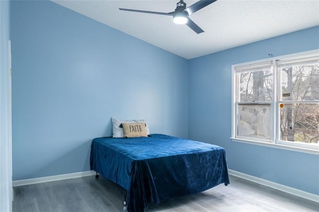 bedroom with ceiling fan, baseboards, and wood finished floors