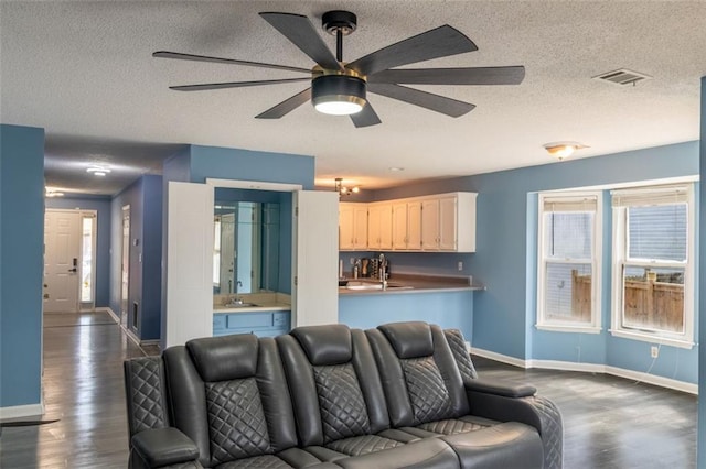 living room with dark wood finished floors, visible vents, ceiling fan, a textured ceiling, and baseboards