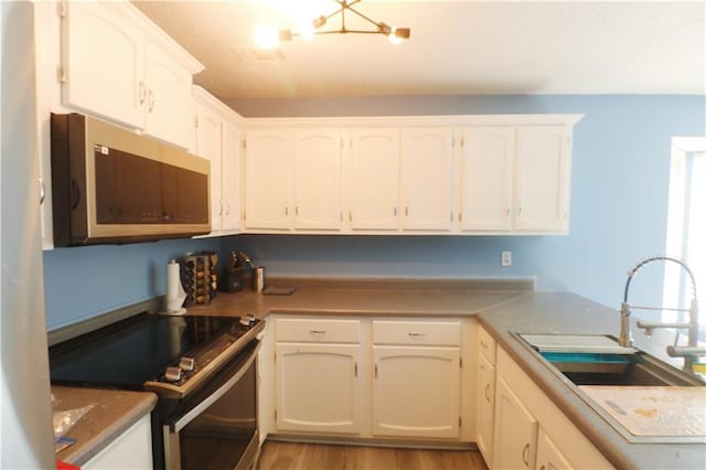 kitchen with stainless steel appliances, light hardwood / wood-style flooring, white cabinetry, and sink