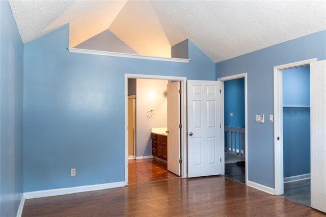 unfurnished bedroom featuring lofted ceiling, dark wood-style floors, baseboards, and a closet